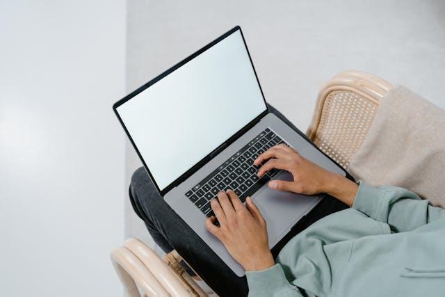 A person holding a laptop on their lap