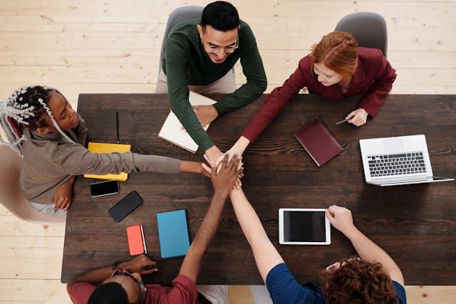 Colleagues putting their hands together above the table