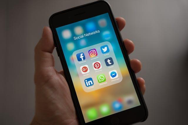 A man holding a phone with social media apps on display