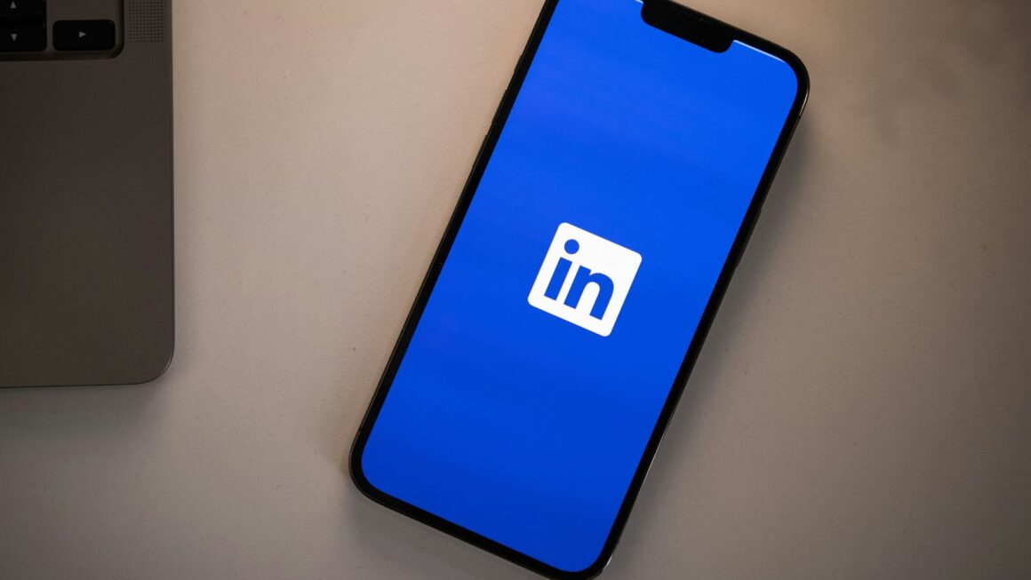A phone displaying the LinkedIn logo on a blue background.