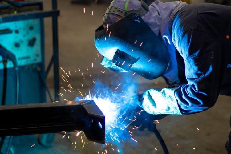 Welder doing metalwork with welding hood
