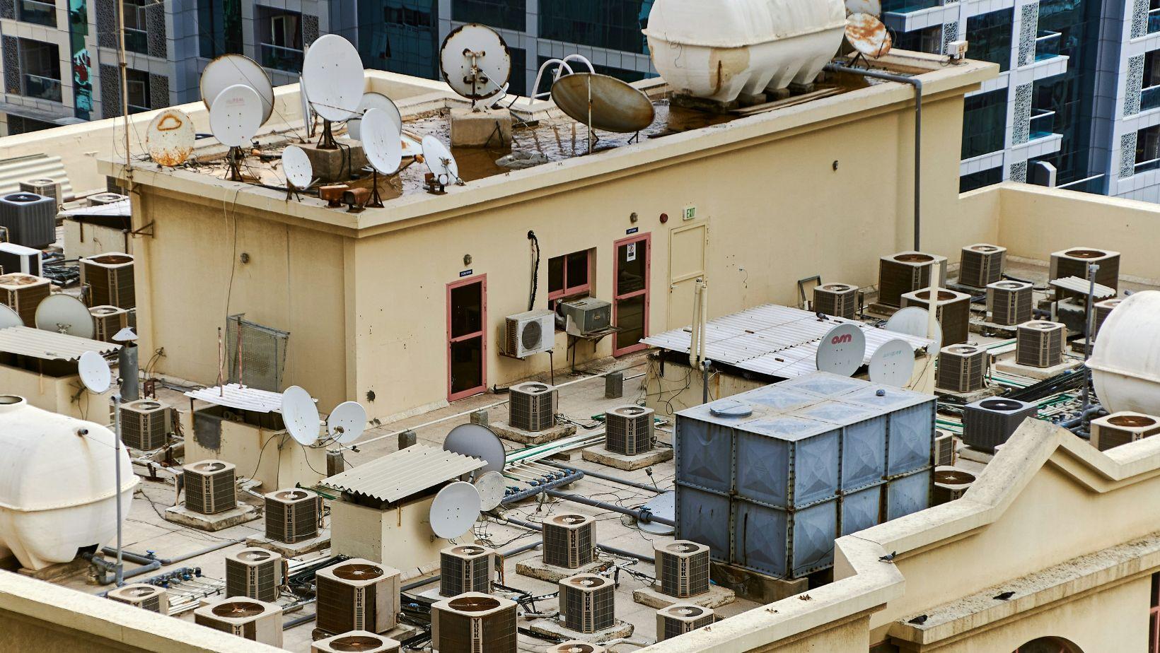 Rooftop of a commercial building with HVAC units and membrane roofing under a clear sky